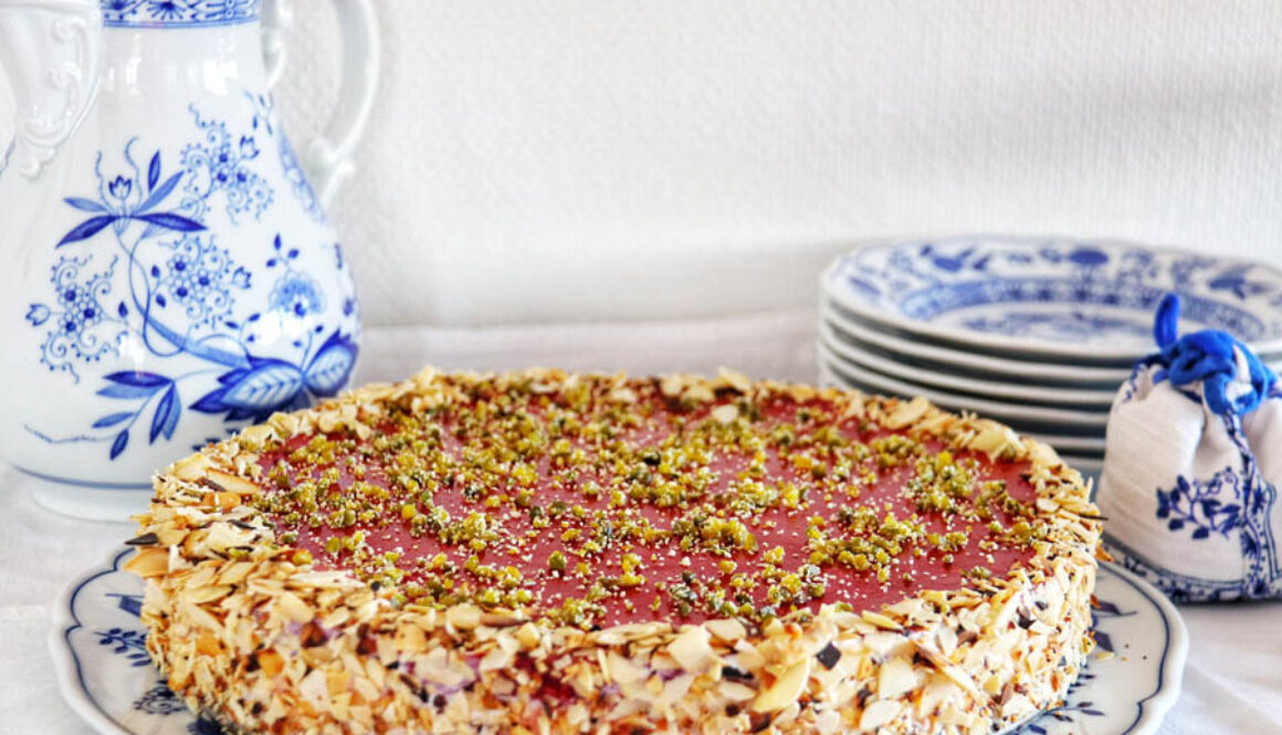 Alessi’s cheesecake with raspberry topping, pistachios and toasted almond crust on a ceramic plate