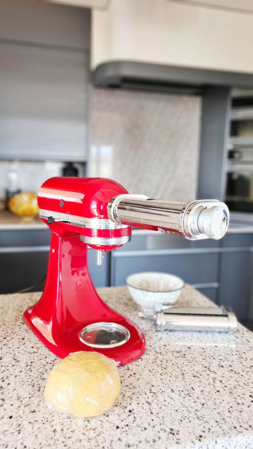Fresh pasta dough beside the KitchenAid pasta machine.