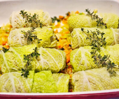 French stuffed cabbage rolls with thyme arranged over vegetables before braising